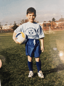 a young boy is holding a soccer ball and wearing a shirt that says tenn academy