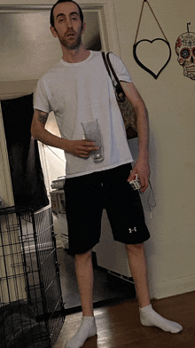 a man wearing under armour shorts holds a glass in his hand