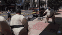 a man in a sumo costume stands on a sidewalk in front of a yellow tape that says do not enter