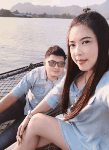 a man and a woman pose for a picture in front of a lake