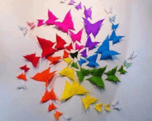 a bunch of colorful origami butterflies flying in a circle on a wall .