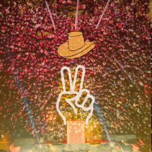 a cowboy hat is above a peace sign in front of a crowd