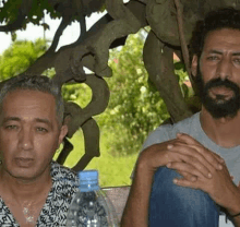 two men with beards are sitting next to each other on a bench .