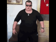 a fat man wearing sunglasses and a black shirt is standing in front of a door .