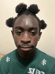 a young man wearing a green sweater with snowflakes on the collar