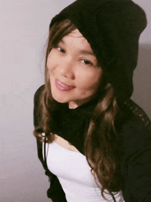 a woman wearing a black hoodie and a white tank top smiles