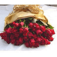 a large bouquet of red roses wrapped in brown paper and tied with a bow .