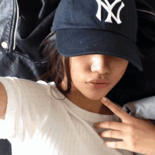 a woman wearing a new york yankees hat taking a selfie