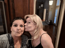 a woman is kissing another woman on the cheek while making a funny face .