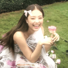 a woman in a floral dress is smiling and holding a rose