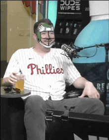 a man wearing a phillies jersey sits in front of a microphone