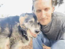 a man kneeling down next to a dog that is smiling