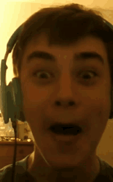 a close up of a person wearing headphones with a surprised look on his face