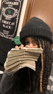 a man holding a stack of money in front of a sign that says cannabis