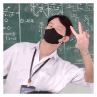 a man wearing a mask is giving a peace sign in front of a blackboard