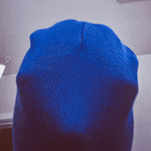 a close up of a blue knitted hat with a purple background