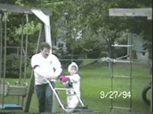 a man is pushing a little girl in a stroller in a park on 9/27/14