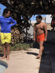 a boy in orange nike shorts is standing next to a boy in a blue shirt