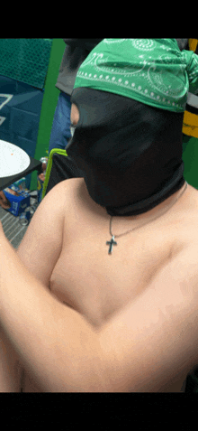 a shirtless man with a green bandana on his head and a cross necklace