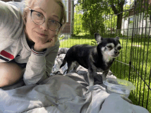 a woman wearing glasses is laying on a bed next to a small dog