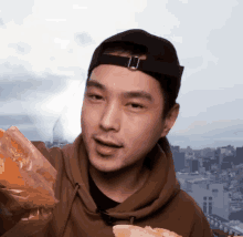 a man wearing a baseball cap holds a bag of food