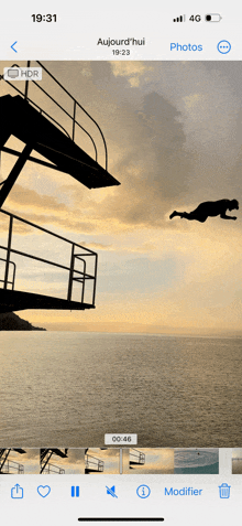 a phone screen shows a picture of a man jumping into the ocean