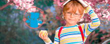 a young boy with glasses is holding a book over his head and eating an apple