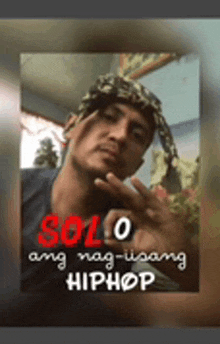 a man with a bandana on his head is standing in front of a sign that says solo ang nag-iisang hiphop .