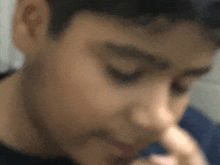 a blurry picture of a young boy 's face with his hand on his nose