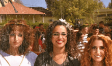 three women are posing for a picture in front of a crowd of people