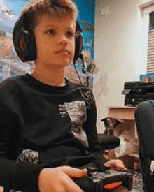 a young boy wearing headphones and holding a video game controller .