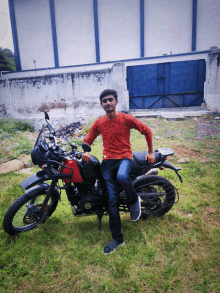 a man in a red shirt is kneeling on a red and black motorcycle with a license plate that says ' a '