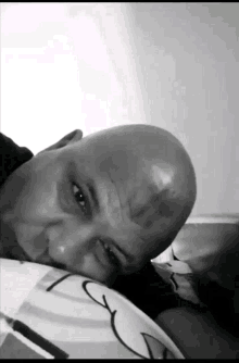 a bald man with a black spot on his forehead rests his head on a pillow