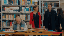 a man sits at a table in a library looking at a book that says ' dictionary ' on it