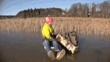 a man wearing a yellow jacket and a red hat with the letter l on it sits in the water