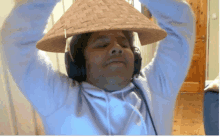 a man wearing headphones and a straw hat with his arms up