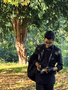 a man in a black shirt is holding a camera with a strap that says canon on it