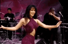 a woman in a red dress is dancing on a stage in front of a band .