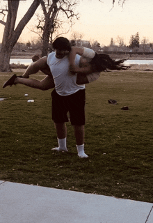 a man in a white shirt is carrying a woman in his arms