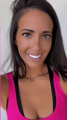 a woman in a pink tank top is smiling