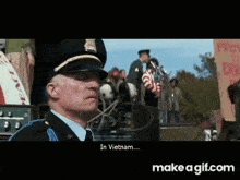 a man in a police uniform is standing in front of a crowd and talking into a microphone in vietnam .