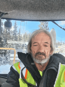 a man with a beard is wearing a yellow and orange vest