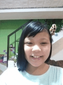 a young girl is taking a selfie in a living room with a stuffed animal on her head .