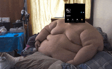 a very fat man is laying on a bed with a phone screen covering his face that says wareck