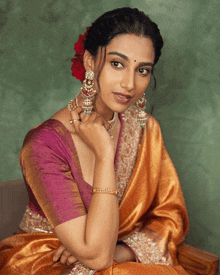 a woman with a flower in her hair wearing a purple blouse and earrings