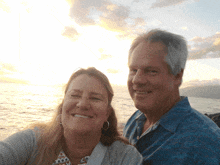 a man and a woman are posing for a picture with the ocean in the background