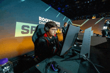 a man sitting in front of a computer with the word rocket league on the wall