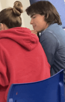 a girl in a red hoodie is sitting next to a boy in a blue shirt