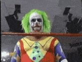 a clown in a wrestling ring with green hair and a tie