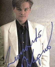 leonardo dicaprio is wearing a white jacket and a blue shirt and has a signature on his picture